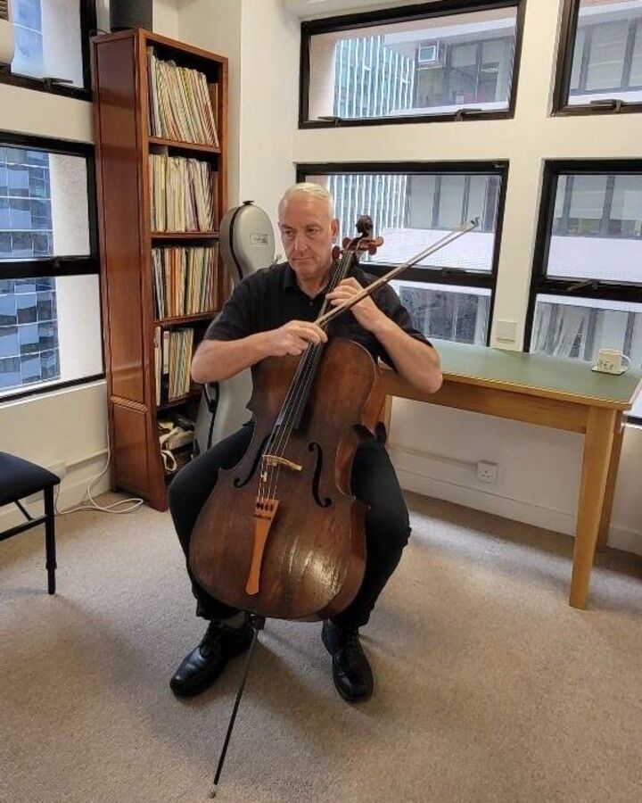 Ron Wilson seated with his cello in the Hong Kong Strings teaching studio